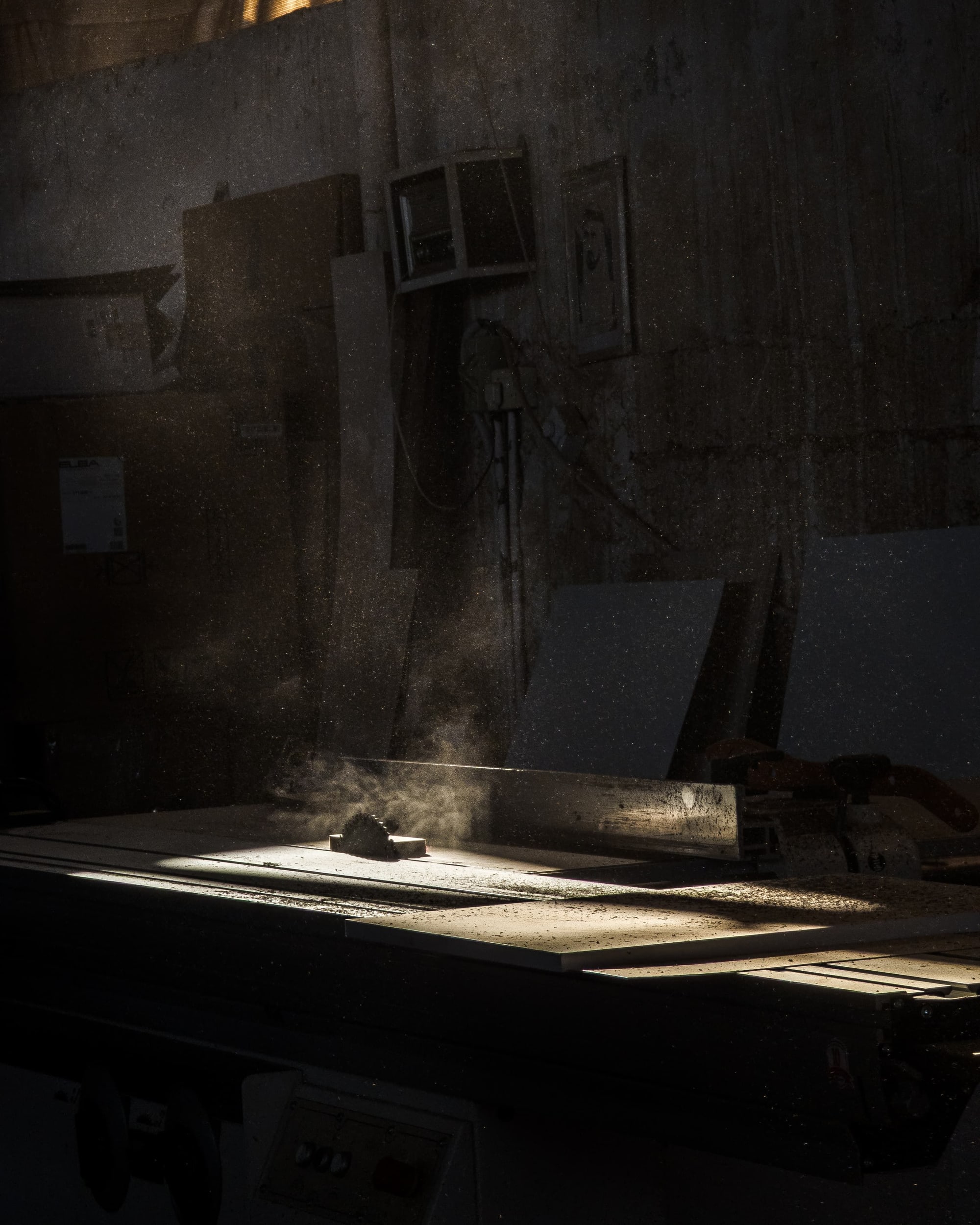 Table saw in a beam of golden workshop light, dust in the air