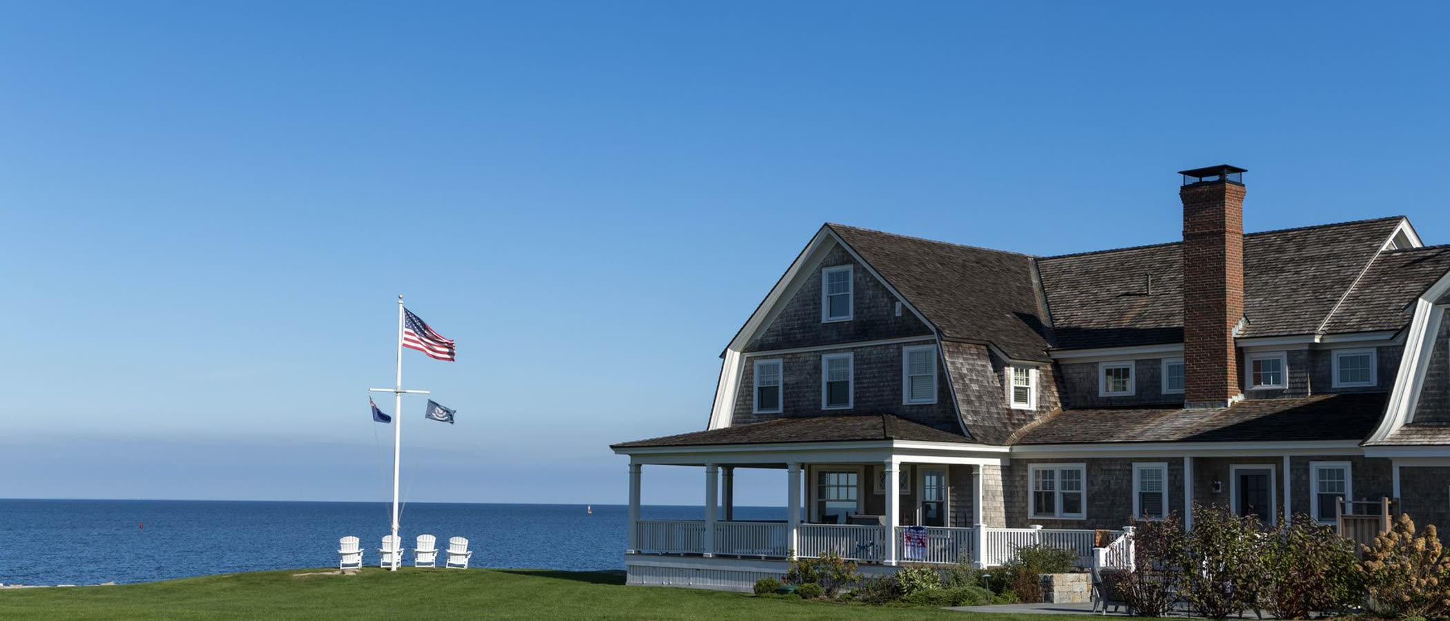 Shingled estate with wraparound porch facing the water, Cape Cod